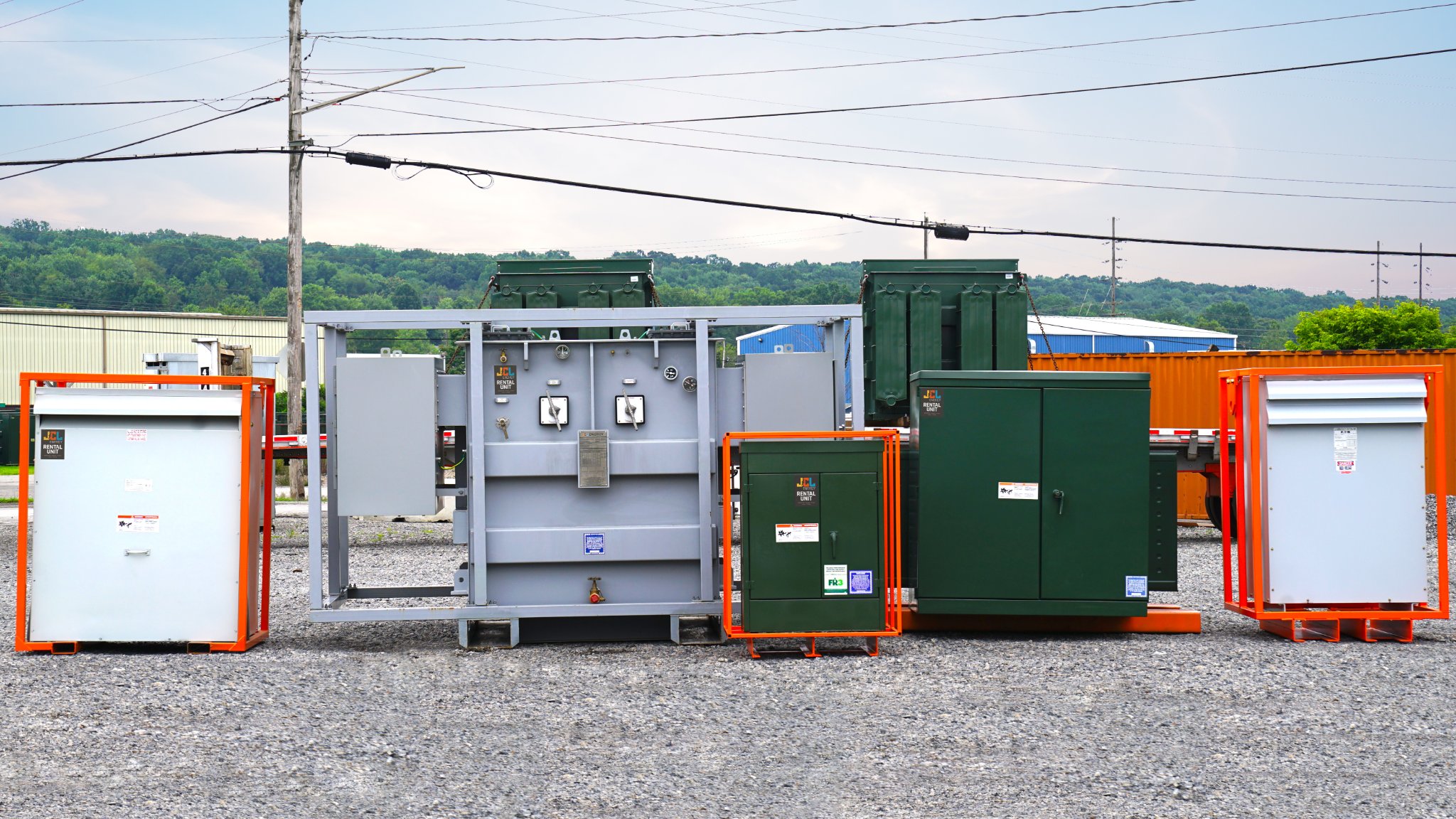 JCL rental transformers in orange shipping frames lined up in the yard, ready to dispatch